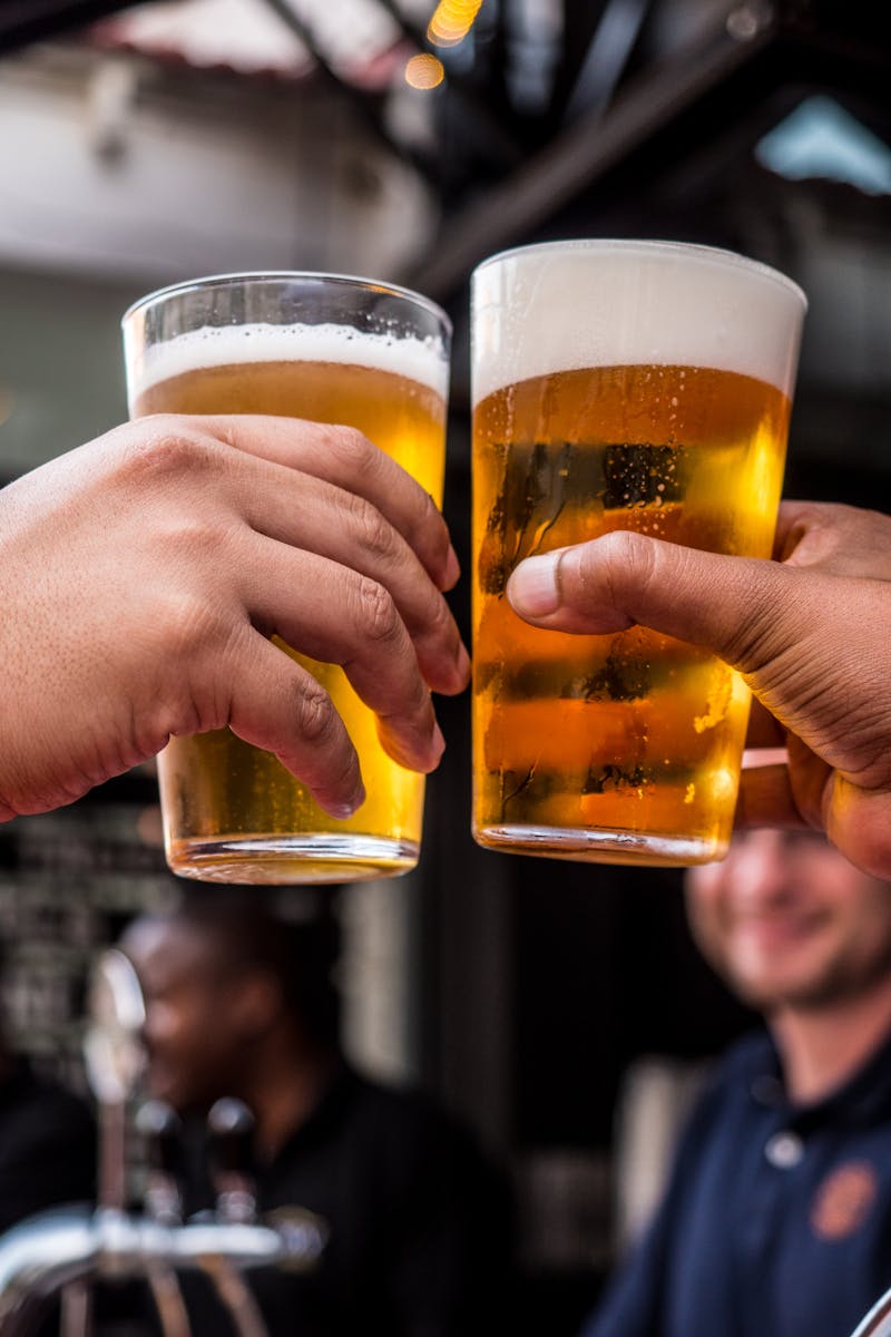 Photo by Tembela Bohle Two Persons Holding Drinking Glasses Filled With Beer